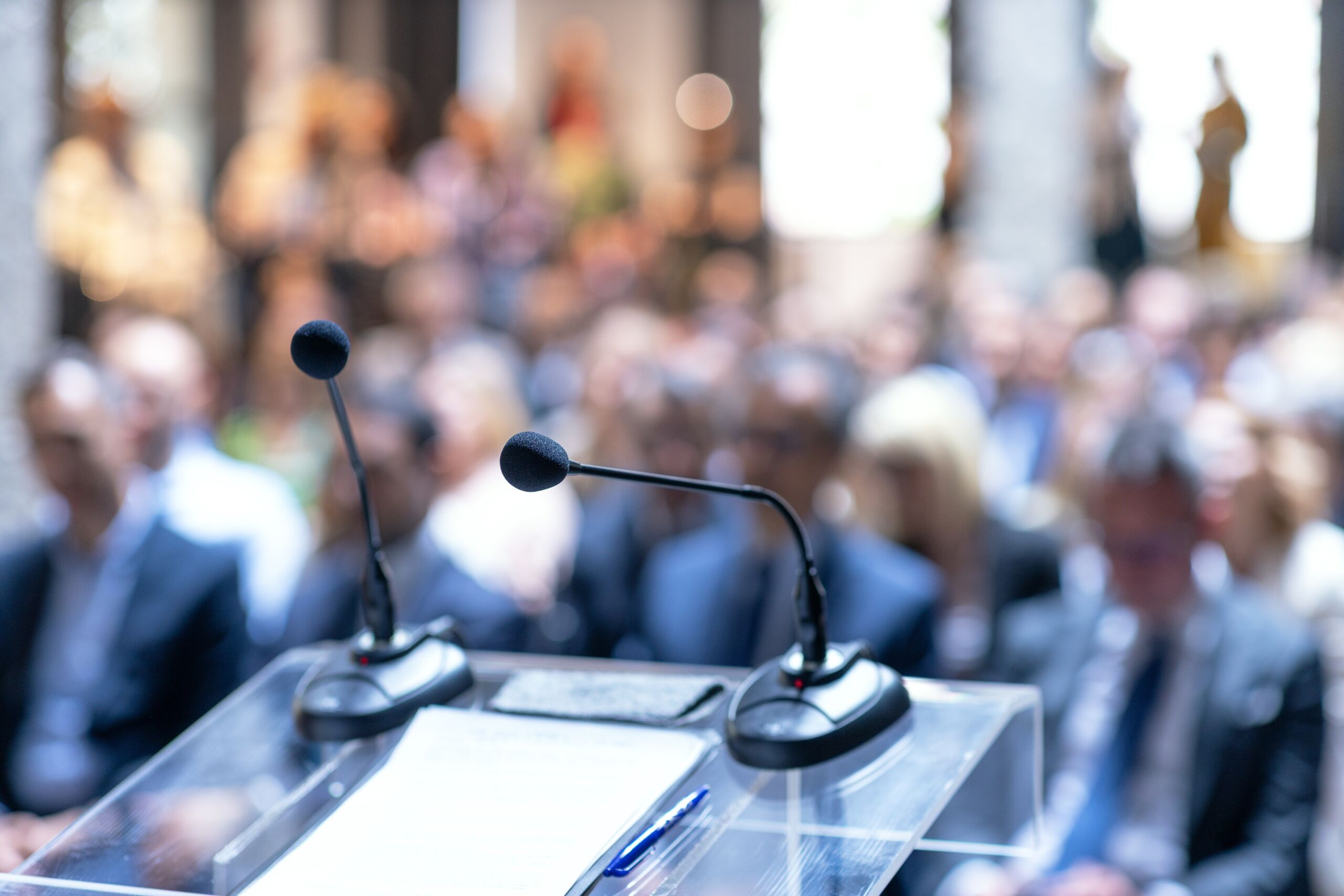 Podium with microphones at a political conference with audience in background